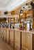 A large light brown wooden drinks bar with beer pumps on, in front of several shelves with bottles on.